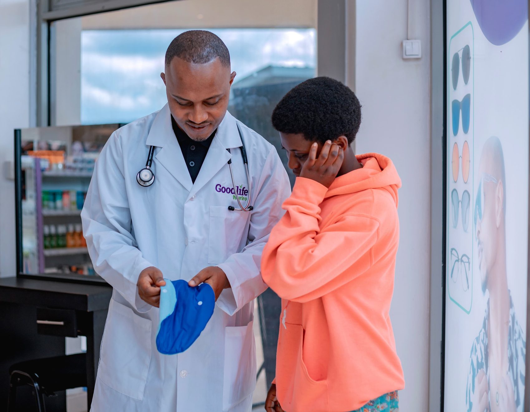 A Goodlife pharmacist showing a reusable menstrual pad to a teenage girl.